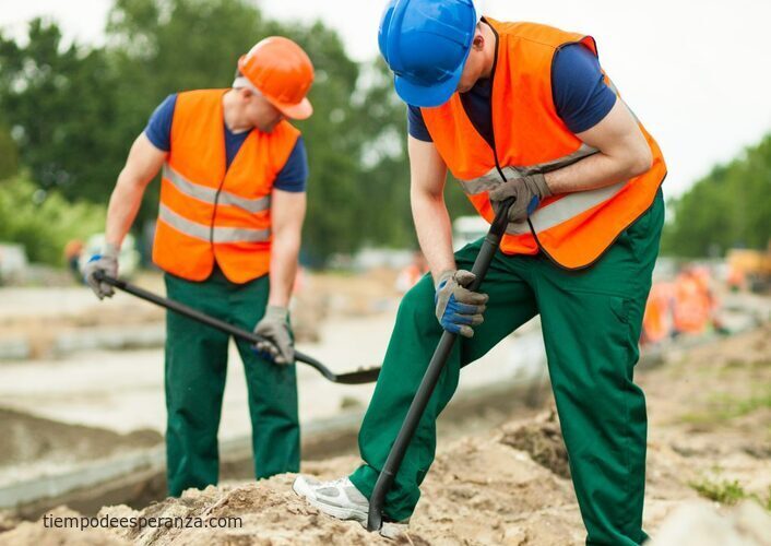 Hombres trabajando en construcción con chalecos anaranjados