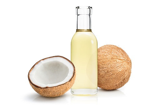 Coconut oil in a bottle and two half cut pieces of coconut