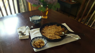 rhubarb crisp in cast iron pan with lilacs in the background
