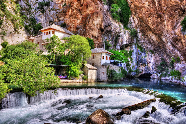 Large hotel on top of a river flowing out from a cavern