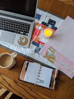 planner, calendar, laptop on desk with coffee mug and a candle