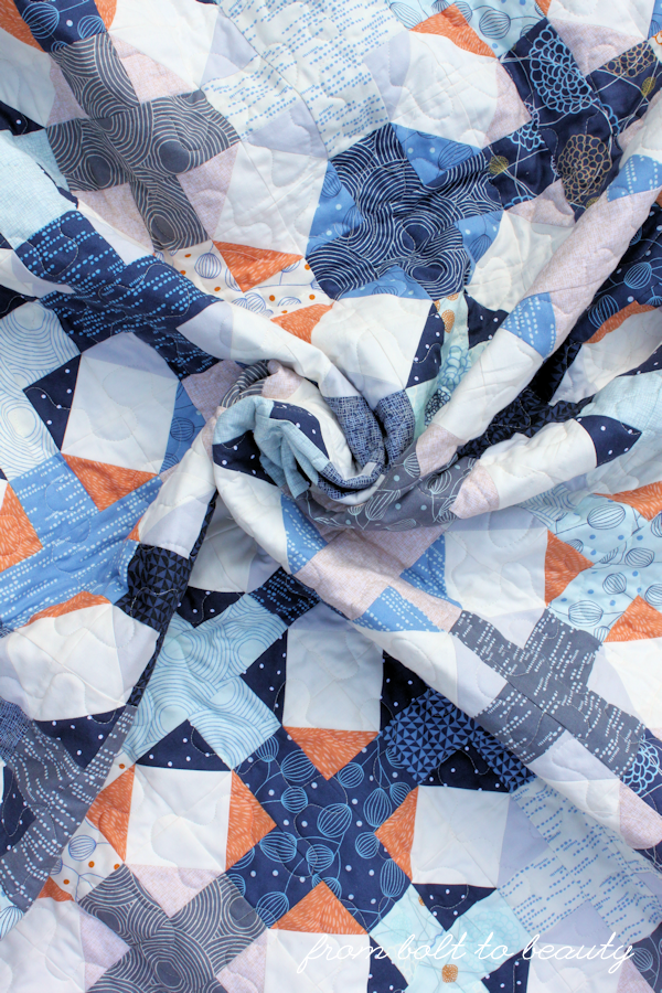 A quilt swirl in blues, grays, oranges, and whites.
