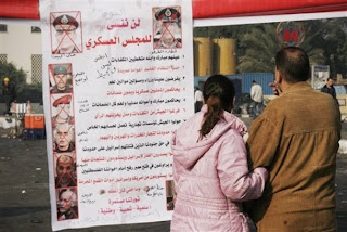 An Egyptian couple looks at an anti-government banner