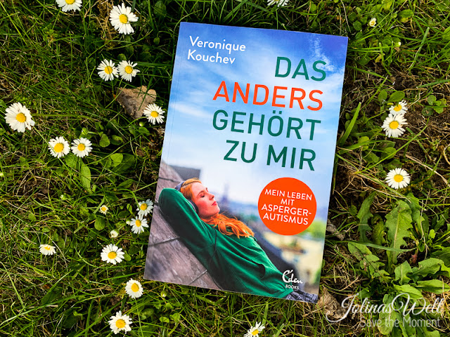 Buch DAS ANDERS GEHÖRT ZU MIR liegt in einer Wiese mit Gänseblümchen