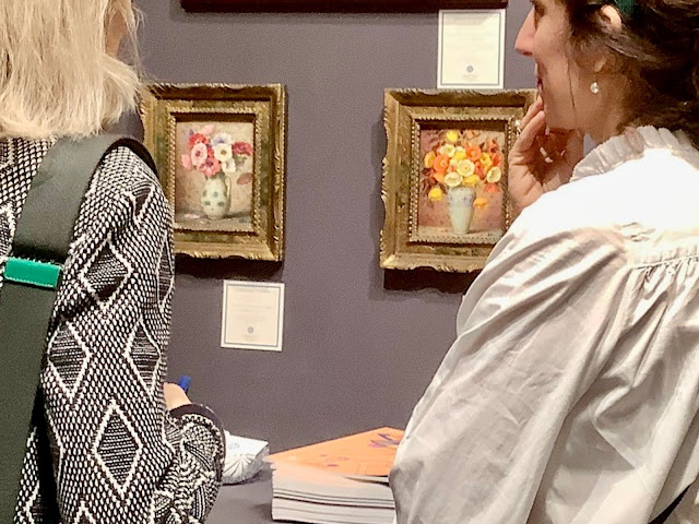 Two women looking at 2 flower paintings