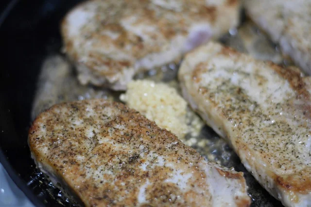 The minced garlic in the pan with the browned pork chops.  