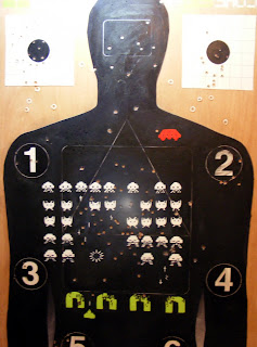 Target 2: Space Invaders, a mixed media painting in progress by Kate MacDonald. 24 x 36 - paint and shooting practice target on wooden panel.