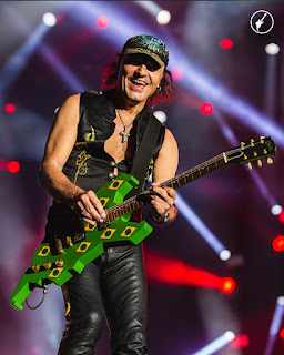 Matthias Jabs no palco tocando a icônica guitarra verde com bandeirinhas do Brasil, utilizada na edição de 1985. 