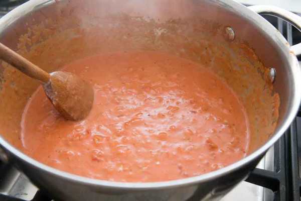 Añadir el tomate triturado a las cebollas. Agregar la vodka, la crema y la ralladura de limón. Aumentar el fuego para a llevar a fuego lento, luego baje el calor para mantener un fuego lento.