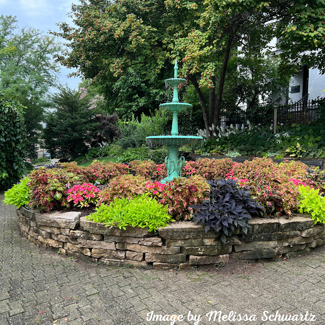 A gorgeous multitiered fountain rises above a patchwork of various colored plants at Period Park in Madison, WI.