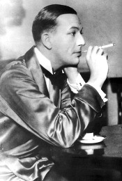 Noel Coward posing with a cigarette holder and wearing a silk dressing gown for his play Private Lives