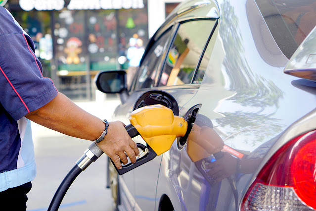 Un hombre utiliza la mano para abrir un surtidor de gasolina o gasóleo. Para repostar un coche aparcado en una gasolinera con un surtidor de gasolina o gasóleo.