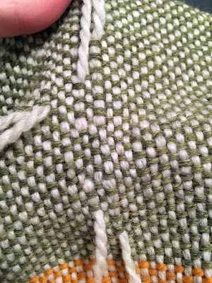 Close up of the same light green and white block. Tails of white yarn emerge vertically from the surface of the fabric in nearly-adjacent rows; it's just posible to see that the white yarn is doubled at either end of the repair, with a single strand running where the light green floats were.