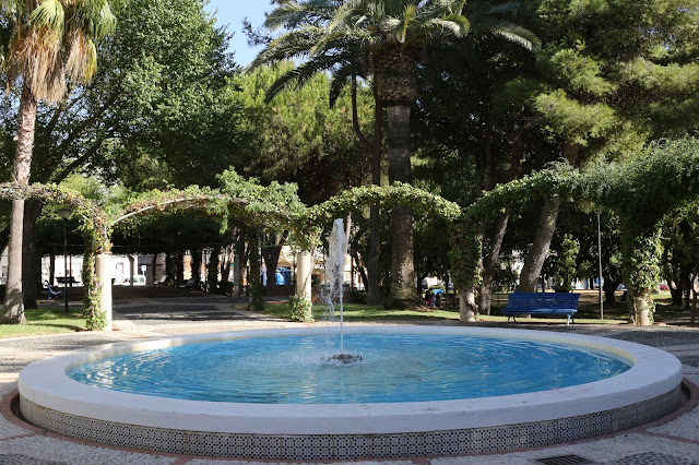 Gran fuente circular en un parque con exuberante vegetación.