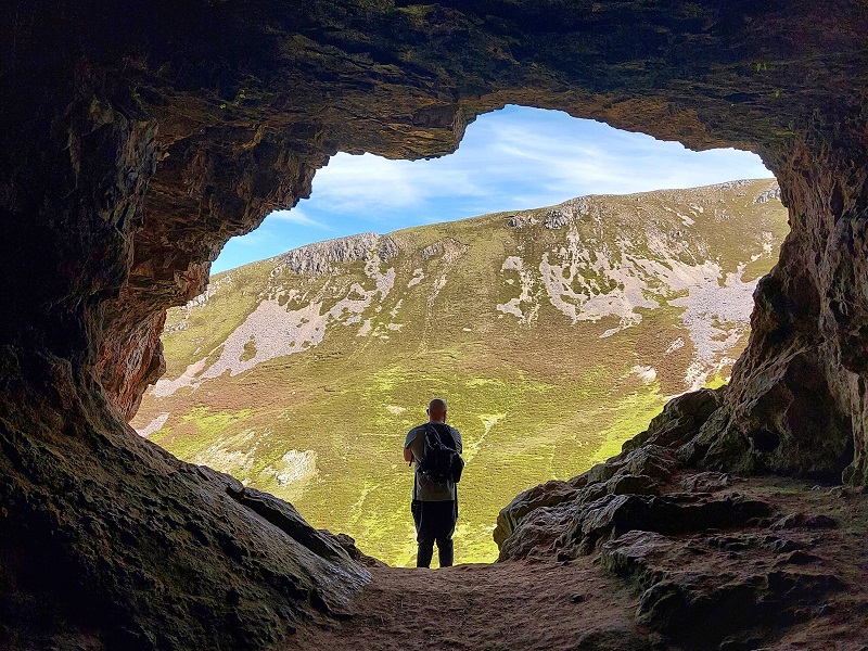 Gordon standing in the entrance to one of the Bone Caves, looking out over sun drenched hills