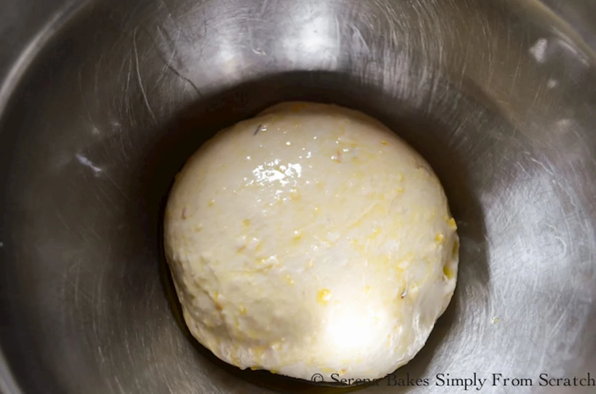 Cheddar Cheese Bun dough ball in a greased stainless steel bowl.