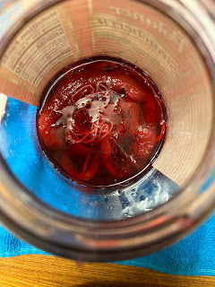looking down into the jar of dye, showing fibers floating in dark red dye