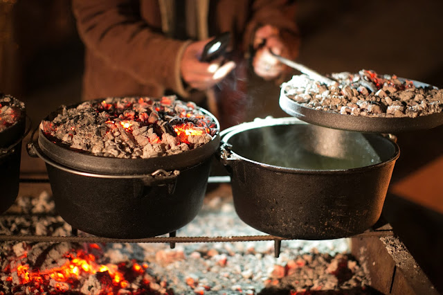 Evan McCommon uses the light on his phone to check on a batch of Dutch oven biscuits