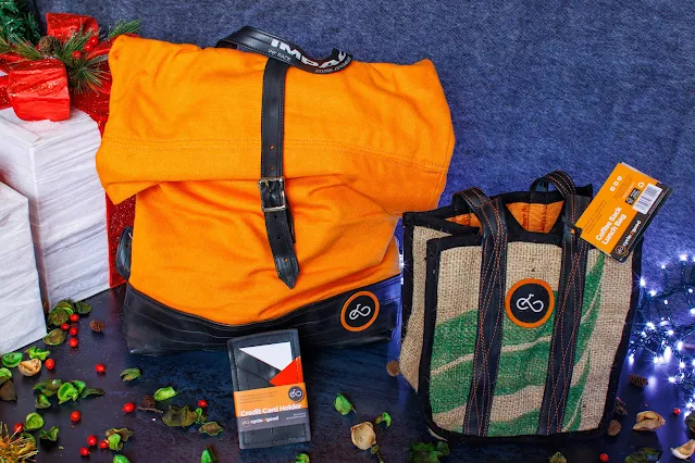 A orange and black rucksack, a small coffee sack hessian bag and a credit card holder made from recycled inner tubes