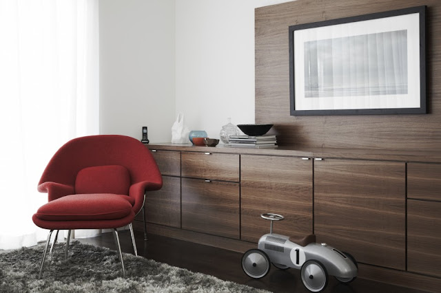 Picture of red chair by the brown wooden furniture on the grey carpet in living room