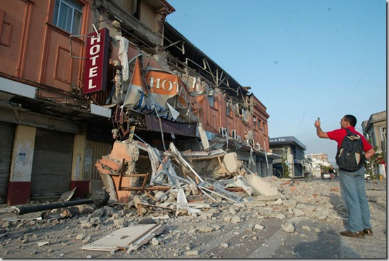 A resident takes photos of a building damaged in Talca, Chile, Saturday, Feb. 27, 2010. A powerful earthquake struck central Chile. (AP Photo/Sebastian Martinez)