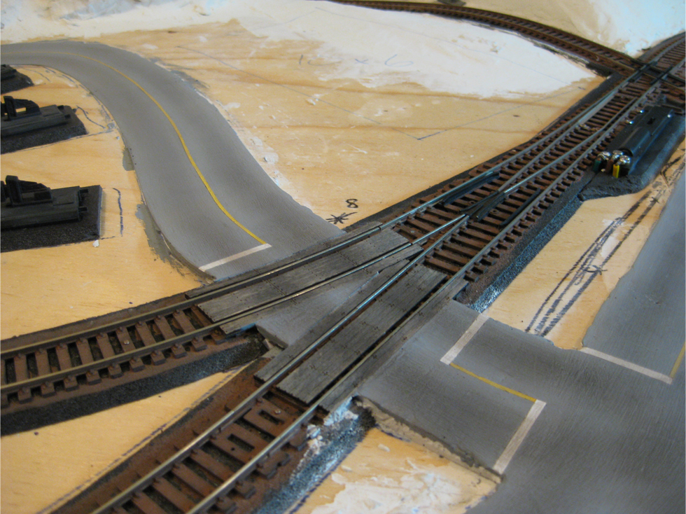 Completed model railroad plaster roads at a turnout and grade crossing