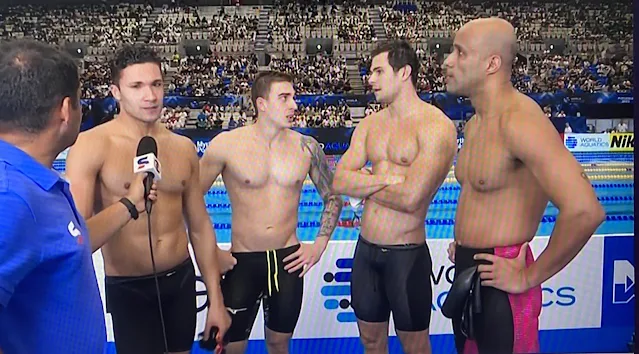 Os 4 nadadores do revezamento masculino estão sem camisa e estão dando entrevista para o Sportv. O repórter está de azul e segurando o microfone