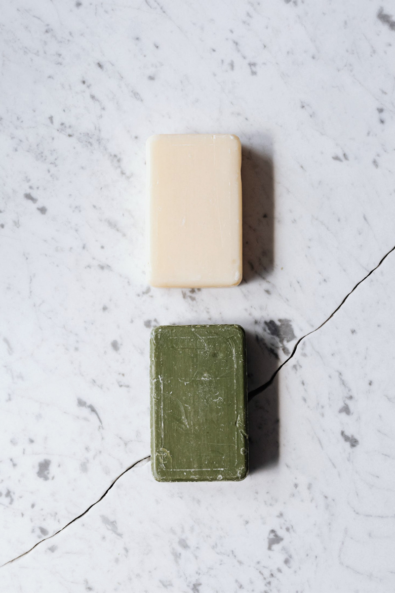 two handmade soaps on a cracked marble table