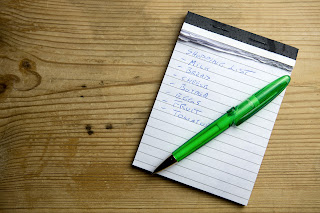 a notepad and pen, with a shopping list on it