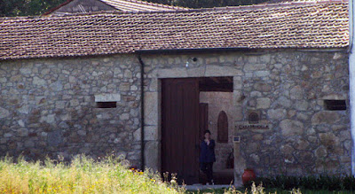 mulher encostada numa porta de uma casa rural