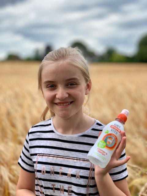 girl in barley field with Get More Vits drink