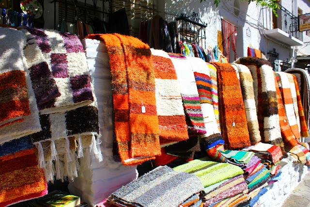 Wielokolorowe dywany tzw. jarapas wywieszone na barierce przy sklepiku z rzemiosłem przy jednej z uliczek Pampaneiry, wiosce niedaleko Grenady.