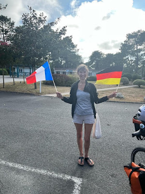 Heike steht auf dem Parkplatz und schwenkt die deutsche und französische Fahne