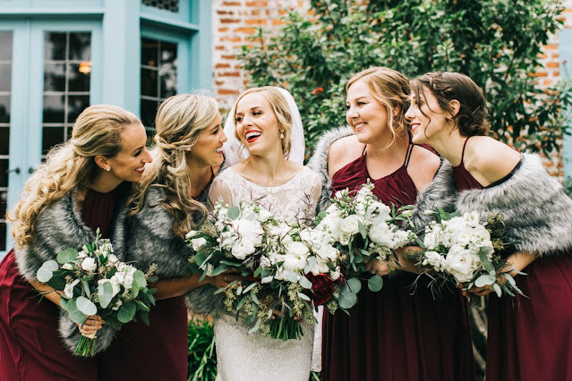 bride with bridesmaids in red dresses with faux fur coverups