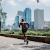 Shirtless man on black shorts running in a city pathway