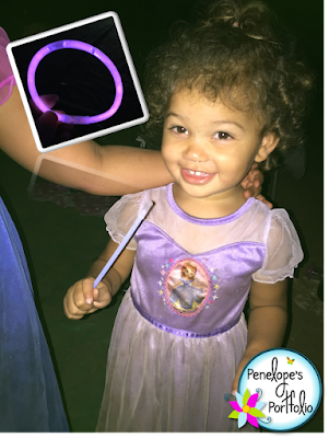 A little girl holding a glow in the dark necklace at night while camping