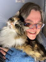 A woman with a calico cat snuggling up against her face
