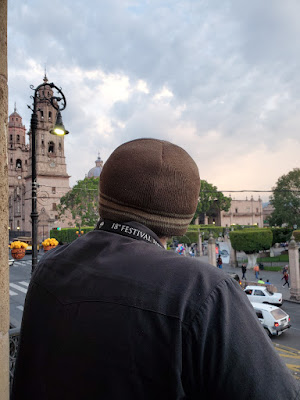 man wearing beanie as see from behind looking out at the main plaza in Morelia.