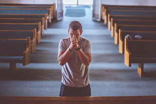 A photo showing a man on his knees with his fingers crossed; praying- Kasha's Pen