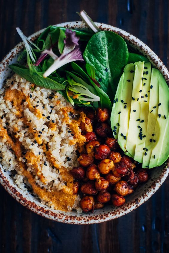 This vegan buddha bowl has it all - fluffy quinoa, crispy spiced chickpeas, and mixed greens, topped with a mouthwatering red pepper sauce!