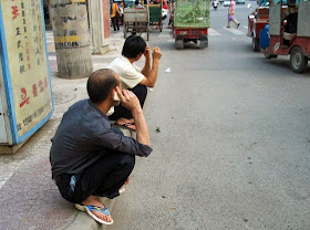 chinese men sitting on their haunches
