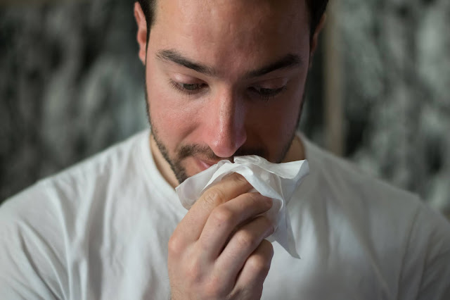 man sneezing:Photo by Brittany Colette on Unsplash