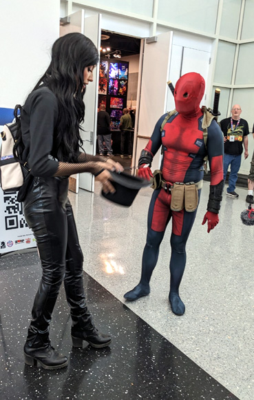 A DEADPOOL cosplayer flirts by showing a magic trick to another fan at Comic Con Revolution in Ontario, CA...on May 20, 2023.
