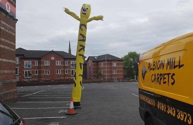 A wacky waving inflatable arm flailing tube man advertising Albion Mill Carpets in Ashton-under-Lyne