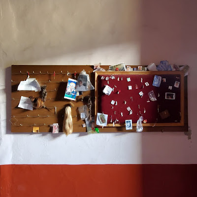 locks of hair, notes, photos, etc hung on a peg board