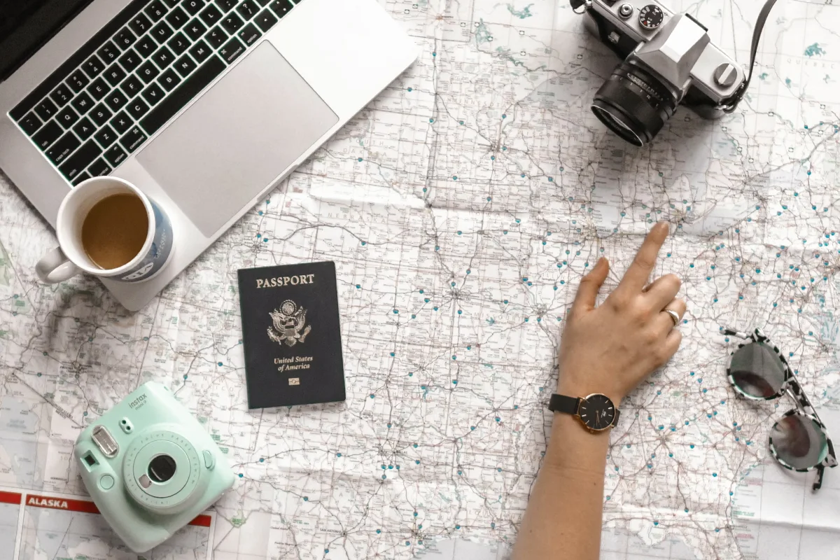 flatlay with a travel map, passport, instax camera and a coffee mug