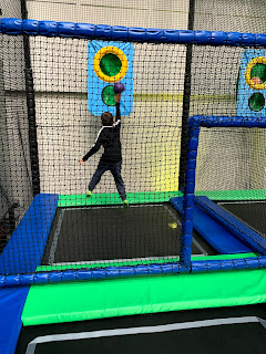 Boy jumping in the air putting a ball into a hole in the wall