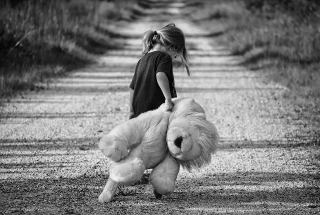 A girl carry a teddy bear with resentment.