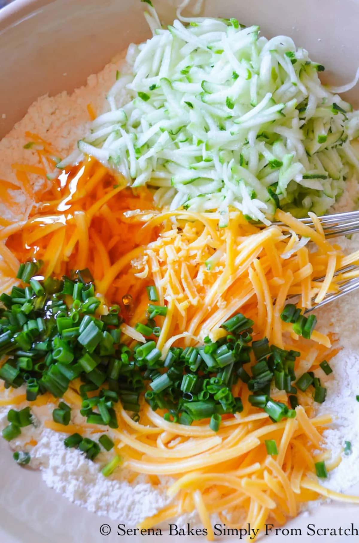 Grated Cheddar Cheese, Grated Zucchini, and Chopped Chives added to flour in a mixing bowl.