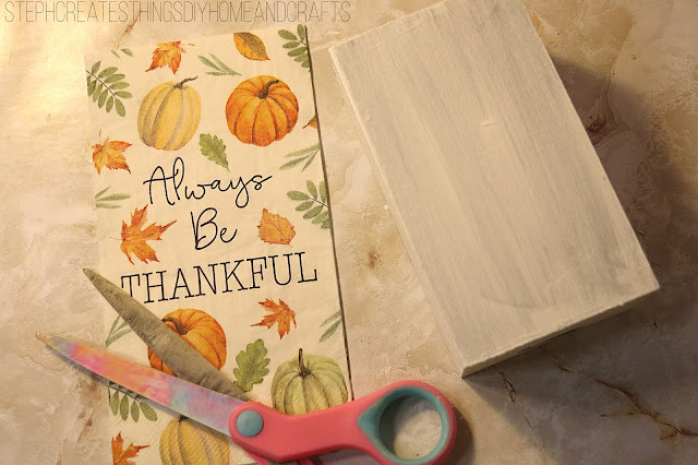 Decorative napkin with pumpkin design, painted crate, and scissors